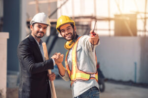 Engineer and construction worker shaking hands at a building site, showing teamwork with a professional industrial construction partner