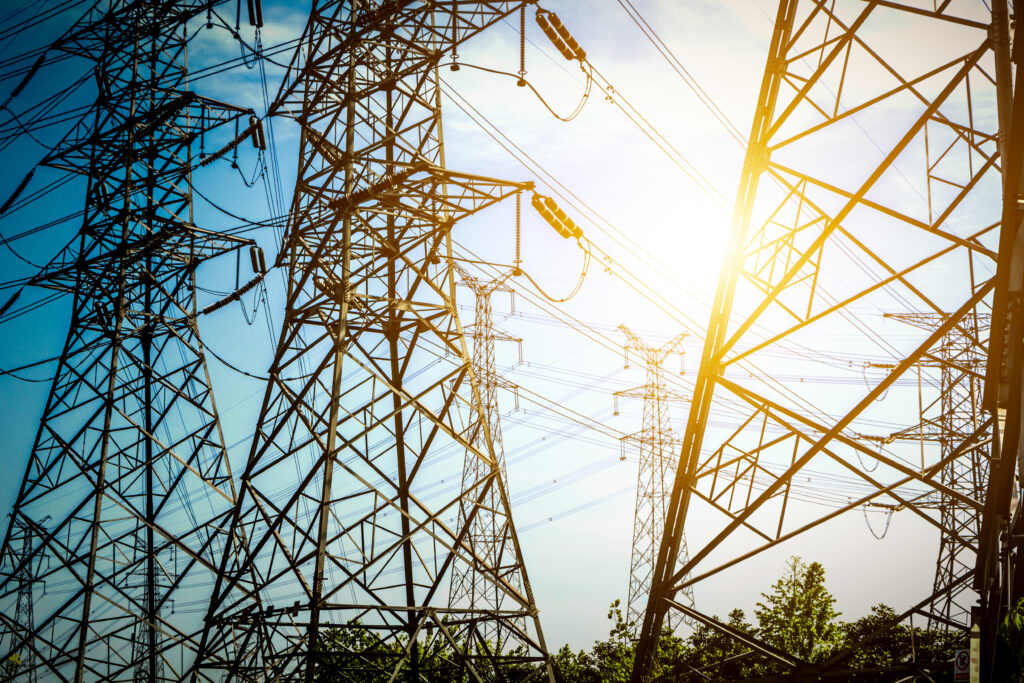 High voltage transmission towers and power lines made of steel structure against blue sky